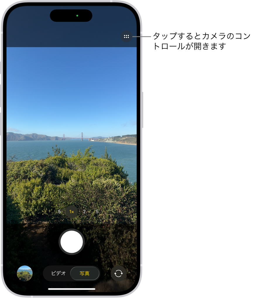 「写真」モードで「カメラ」が開いています。右上隅には「カメラコントロール」ボタンがあります。左下隅には写真およびビデオビューアボタンがあります。下部中央には写真撮影ボタン、右下隅には背面カメラ選択ボタンがあります。