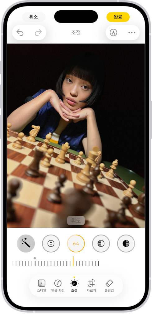 중앙에 사진이 있는 편집 화면. 화면 하단에는 왼쪽에서 오른쪽으로 스타일, 인물 사진, 조절, 자르기 및 클린업 버튼이 있음. 조절 버튼이 선택되어 있고, 사진의 휘도를 조절할 수 있는 슬라이더가 있음. 화면 왼쪽 상단 모서리에는 취소 버튼이 있고, 오른쪽 상단 모서리에는 완료 버튼이 있음.