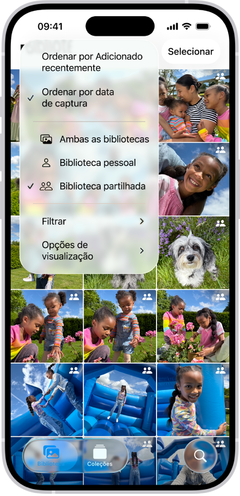 Uma fototeca partilhada em iCloud na aplicação Fotografias. O botão “Biblioteca partilhada” no canto inferior esquerdo está selecionado e “Biblioteca partilhada” está selecionada numa lista de opções da biblioteca. Todas as fotografias apresentadas na biblioteca têm um emblema de biblioteca partilhada no canto superior direito.
