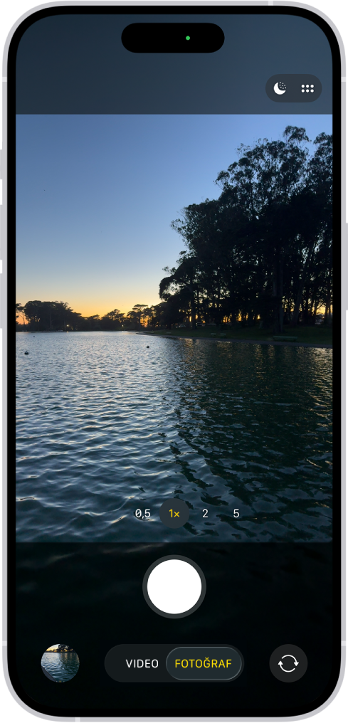 Fotoğraf modunda Kamera ekranı. Vizörde bir gece sahnesi var. Gece ve Kamera Denetimleri modu düğmeleri ekranın sağ üst köşesinde görünüyor. Ekranın en altında, soldan sağa doğru Fotoğraf ve Video Görüntüleyici düğmesi, Video ve Fotoğraf Modu ve Arkaya Bakan Kamerayı Seç düğmesi var.