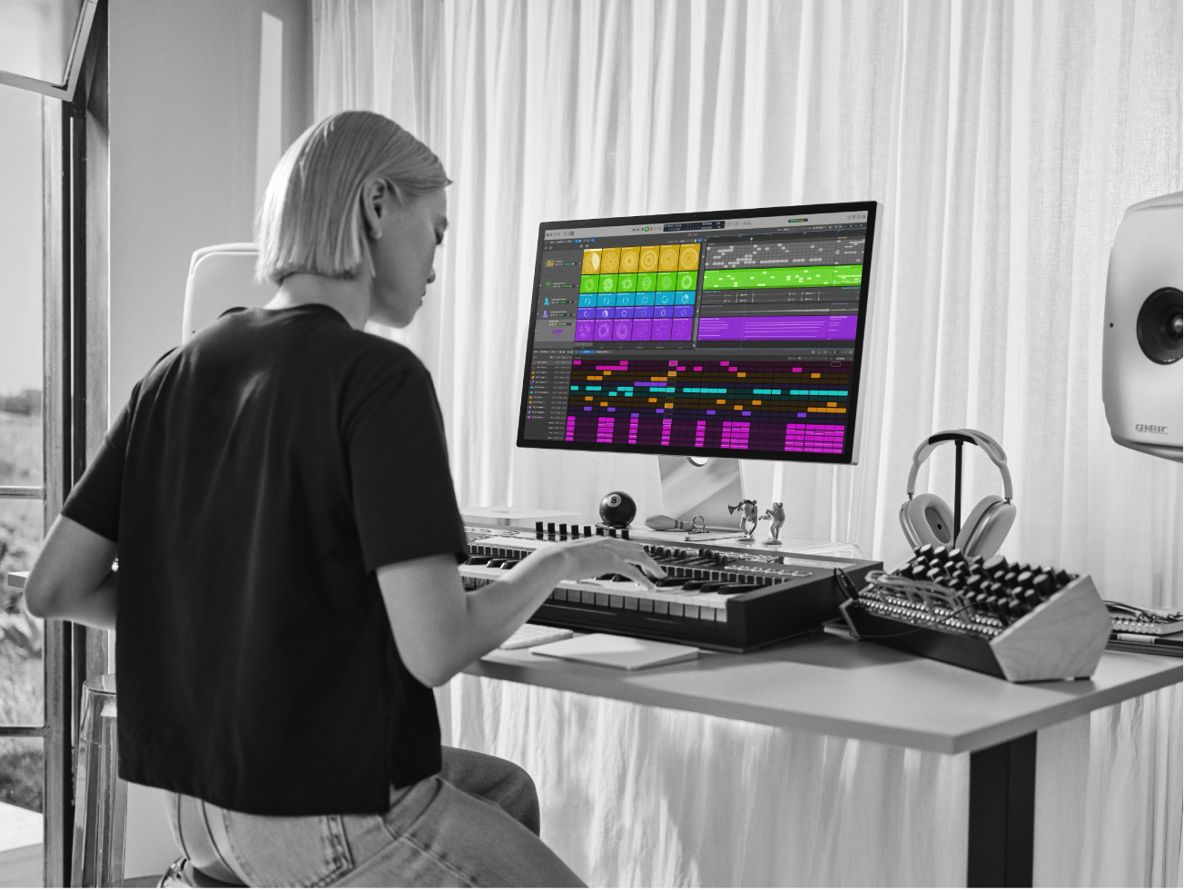 Proyecto de Logic&nbsp;Pro mostrado en un Mac&nbsp;Studio mientras se toca un teclado MIDI.
