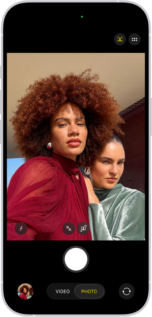 The Camera screen in Photo mode. Within the camera frame, the subjects are taking a selfie.