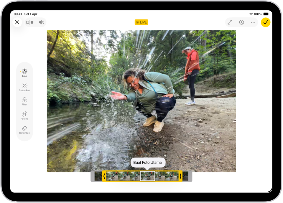 Live Photo ada di bagian tengah layar Edit di app Foto. Penampil bingkai terdapat di bagian bawah video dan garis kuning terdapat di sekitar bingkai yang dipilih untuk disertakan di Live Photo yang diedit; satu bingkai dipilih untuk membuat foto utama. Tombol pengeditan berada di sisi kiri layar, dari atas ke bawah, Live Photo, Sesuaikan, Filter, dan Potong. Live Photo dipilih.