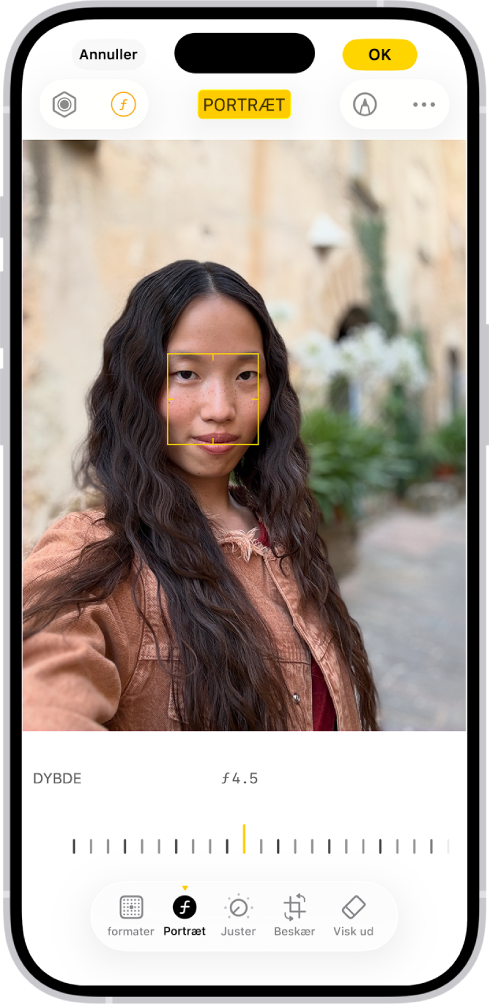 Redigeringsskærmen i appen Fotos med et portræt i midten. Under fotoet ses et mærke til justering af indstillingen Dybdejustering. Fra venstre mod højre under mærket findes knapperne Format, Portræt, Juster, Filtre, Beskær og Visk ud. Knappen Portræt er valgt.