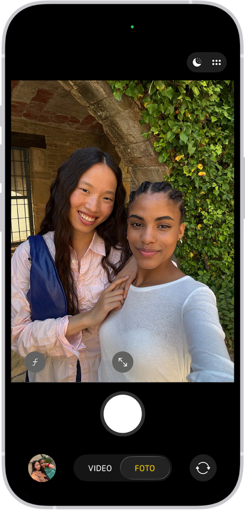La pantalla de la app Cámara en el modo Foto. Dentro del cuadro de la cámara, las personas se están tomando una selfie.