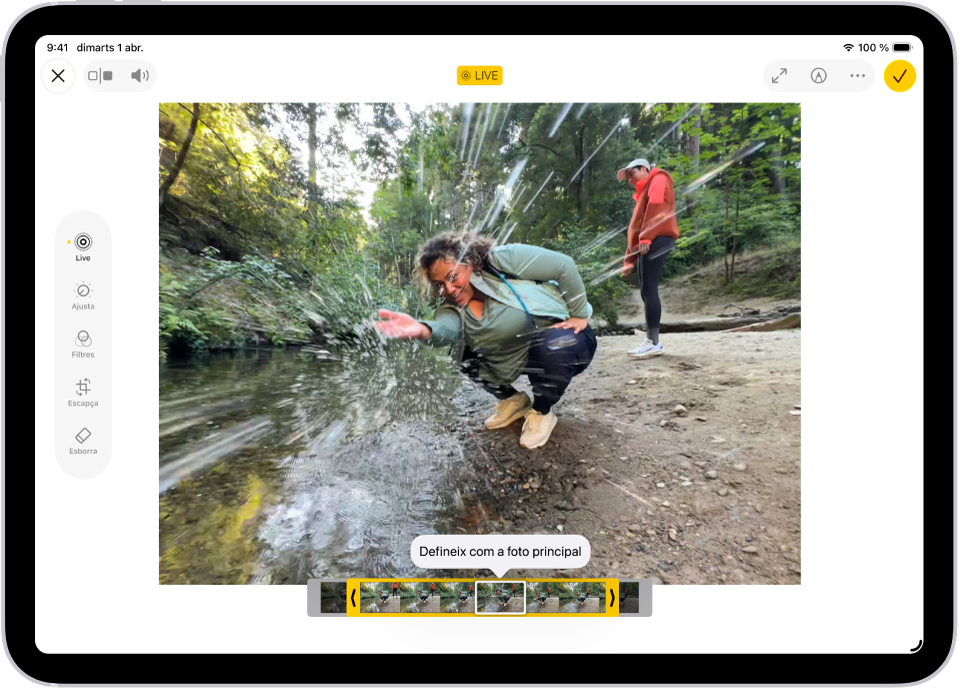 Una Live Photo és al mig de la pantalla d’edició de l’app Fotos. El visor de fotogrames apareix a la part inferior del vídeo i es veu un contorn de color groc seleccionant els fotogrames que s’inclouran a la Live Photo editada. Un únic fotograma està seleccionat per convertir-lo en foto clau. Les eines d’edició són al costat esquerre de la pantalla: de dalt a baix, “Live Photo”, “Ajusta”, “Filtres” i “Escapça”. Se selecciona “Live Photo”.