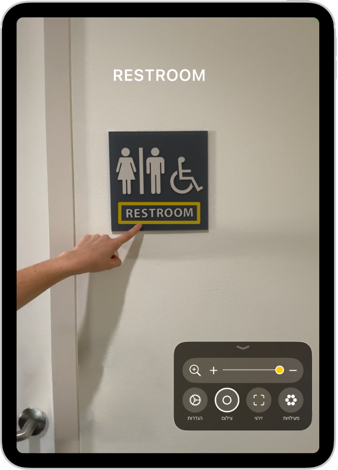 היישום ״זכוכית מגדלת״ מזהה אצבע שמצביעה לעבר מלל על קיר.