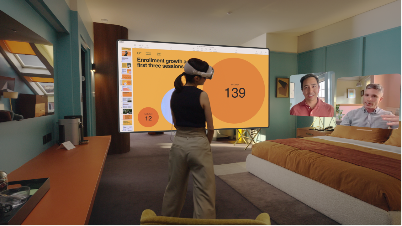 A person wearing Apple Vision Pro and having a FaceTime call. The tiles for others on the call are visible next to a shared screen.
